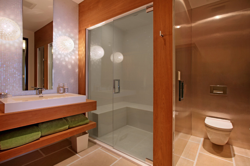 Modern inredning av ett badrum, med ett fristående handfat, öppna hyllor, skåp i mellenmörkt trä, en dusch i en alkov, en vägghängd toalettstol, vit kakel och mosaik