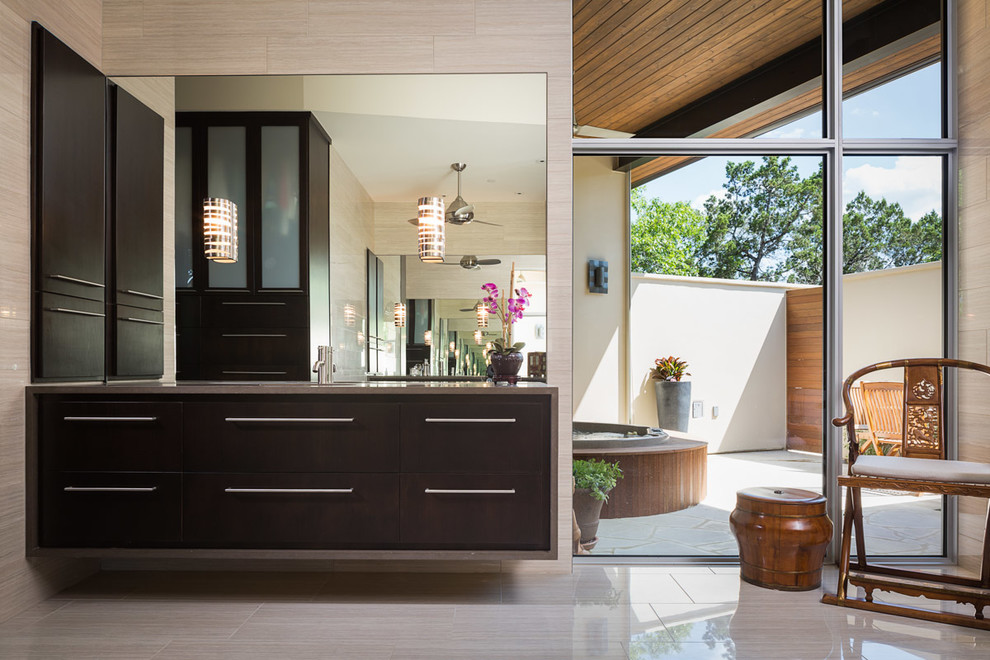 Photo of a large contemporary ensuite bathroom in Austin with flat-panel cabinets, dark wood cabinets, beige tiles, stone tiles, beige walls, ceramic flooring and a submerged sink.