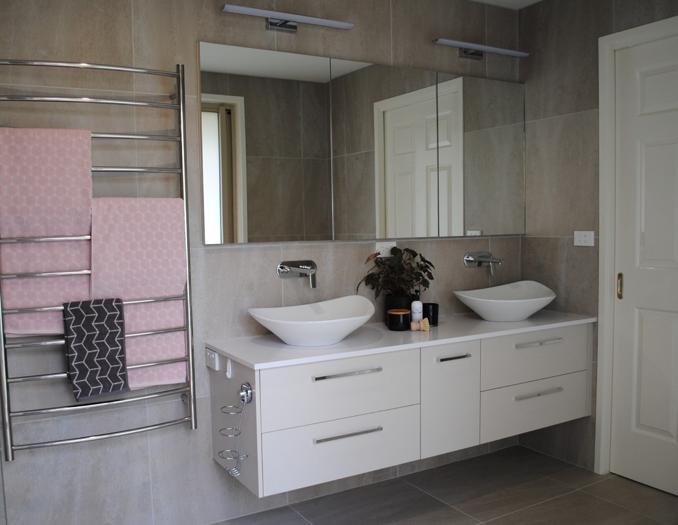 Inspiration for a large contemporary ensuite bathroom in Other with flat-panel cabinets, grey cabinets, a corner shower, a one-piece toilet, grey tiles, ceramic tiles, grey walls, ceramic flooring, a vessel sink, solid surface worktops, grey floors, a hinged door and white worktops.