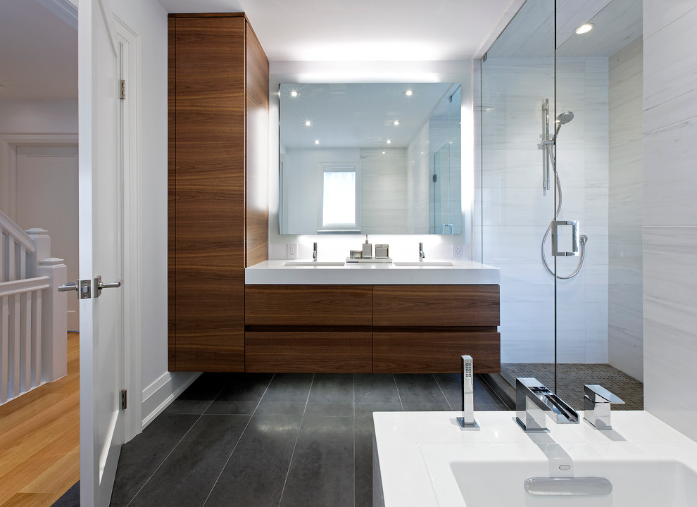 На фото: ванная комната в современном стиле с врезной раковиной, плоскими фасадами, темными деревянными фасадами, отдельно стоящей ванной, угловым душем, серой плиткой, белыми стенами и полом из керамической плитки с