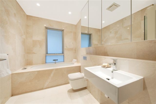 Стильный дизайн: большая ванная комната в стиле модернизм с мраморной столешницей, отдельно стоящей ванной, угловым душем, унитазом-моноблоком, белой плиткой, керамической плиткой, бежевыми стенами, полом из керамической плитки и душевой кабиной - последний тренд