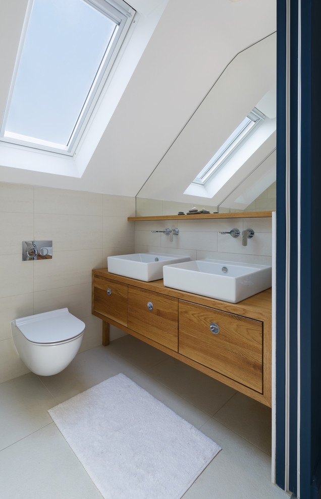 Inspiration for a small contemporary ensuite bathroom in London with beaded cabinets, medium wood cabinets, a wall mounted toilet, beige tiles, ceramic tiles, white walls, ceramic flooring, a vessel sink and wooden worktops.