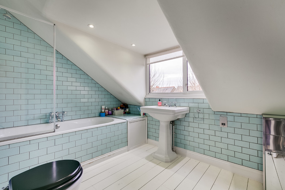 ロンドンにある中くらいなコンテンポラリースタイルのおしゃれな浴室 (ドロップイン型浴槽、シャワー付き浴槽	、一体型トイレ	、青いタイル、サブウェイタイル、白い壁、塗装フローリング、ペデスタルシンク、白い床) の写真