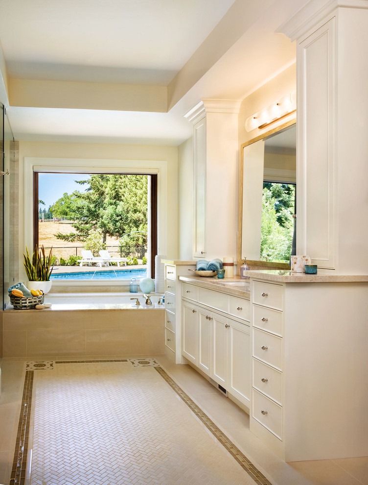 Diseño de cuarto de baño clásico con armarios con paneles empotrados, puertas de armario blancas, bañera encastrada sin remate, baldosas y/o azulejos beige y paredes beige