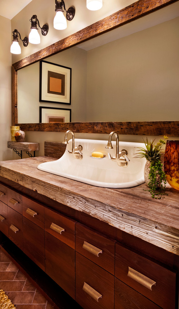 Modelo de cuarto de baño tradicional renovado con lavabo de seno grande, armarios con paneles lisos, puertas de armario de madera en tonos medios, encimera de madera y paredes beige