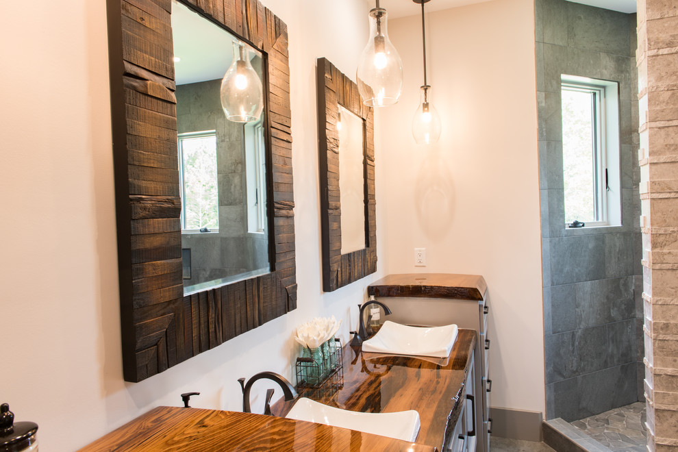 This is an example of a large rustic ensuite bathroom in Charleston with shaker cabinets, grey cabinets, a freestanding bath, a walk-in shower, beige walls, a built-in sink, wooden worktops, grey floors, an open shower and brown worktops.