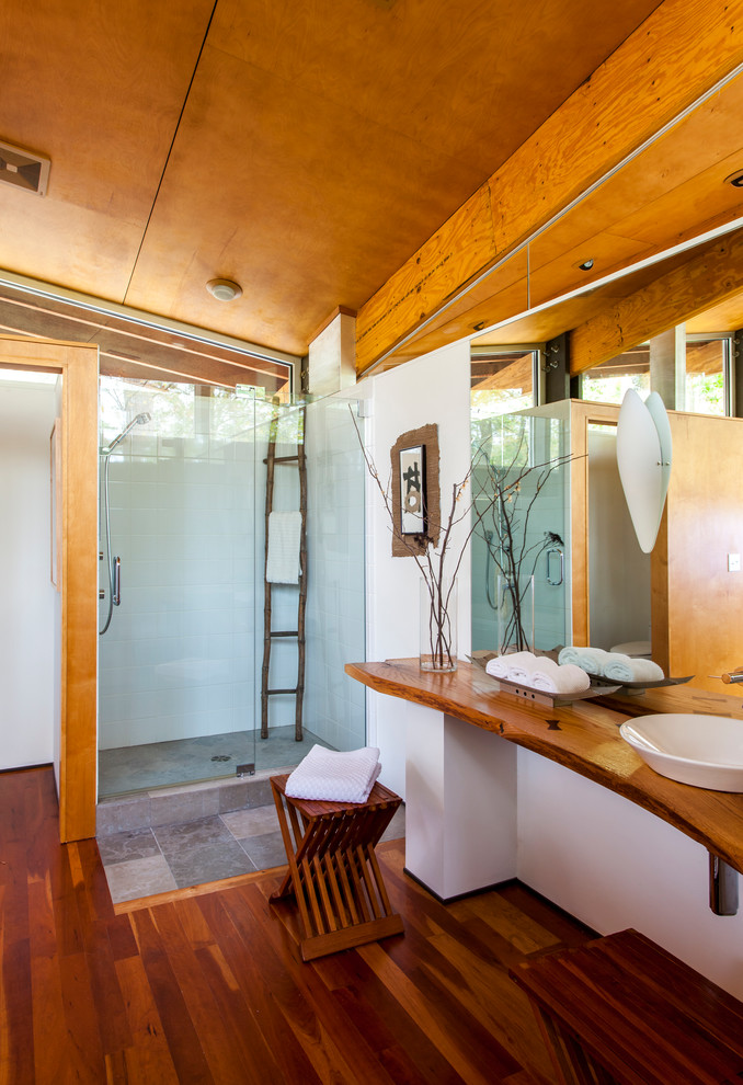 Bild på ett funkis badrum, med ett fristående handfat, träbänkskiva, en dusch i en alkov och vit kakel