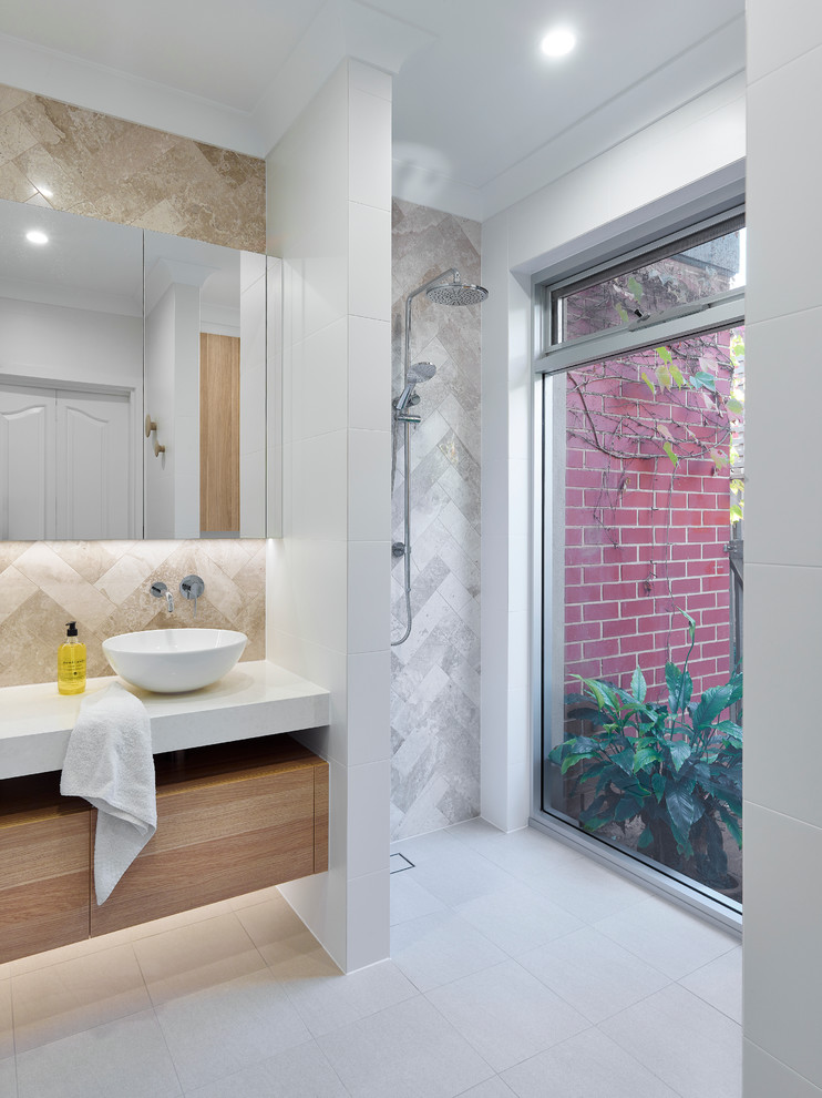 Пример оригинального дизайна: маленькая ванная комната в современном стиле с светлыми деревянными фасадами, открытым душем, раздельным унитазом, серой плиткой, белыми стенами, полом из керамической плитки, душевой кабиной, настольной раковиной, столешницей из искусственного кварца, открытым душем, плиткой из известняка, серым полом, белой столешницей и окном для на участке и в саду