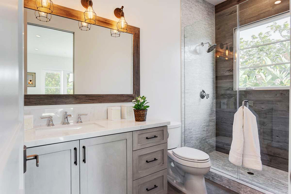 Klassisches Duschbad mit Schrankfronten im Shaker-Stil, Duschnische, Wandtoilette mit Spülkasten, grauen Fliesen, Unterbauwaschbecken, grauen Schränken und Falttür-Duschabtrennung in Los Angeles