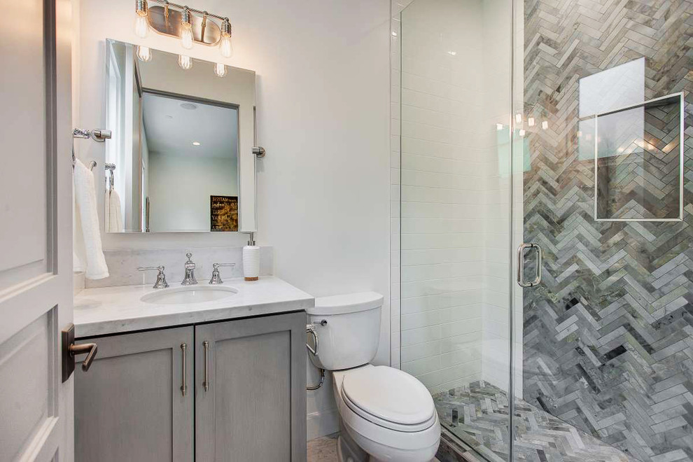 Aménagement d'une salle de bain classique avec un placard à porte shaker, un carrelage gris, un carrelage blanc, un mur blanc, un lavabo encastré, des portes de placard grises et une cabine de douche à porte battante.