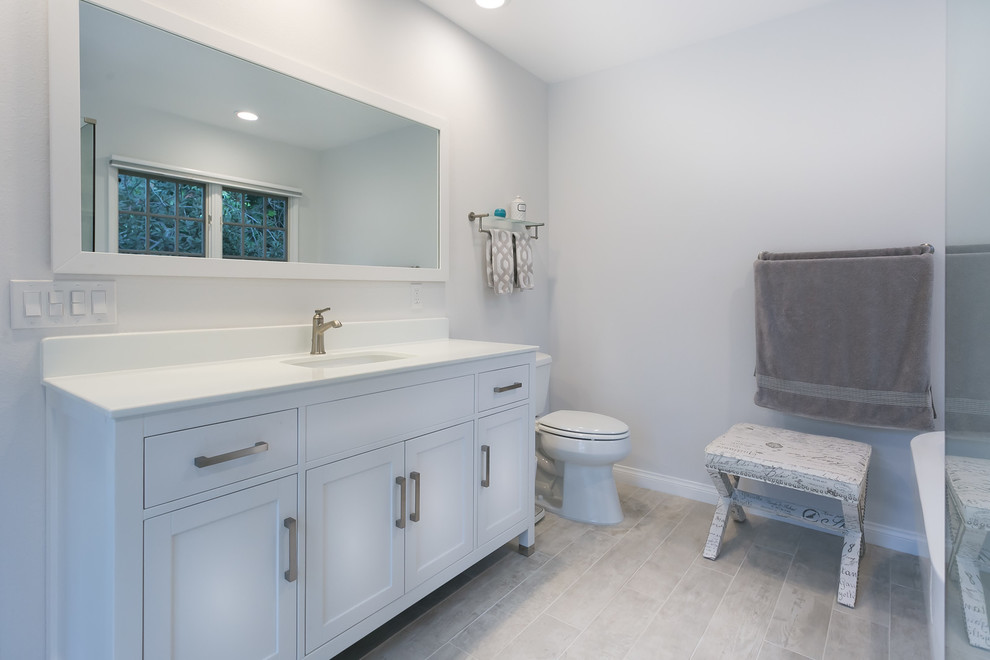 Cette image montre un grand sauna minimaliste avec un lavabo encastré, WC séparés, un placard à porte shaker, des portes de placard blanches, une baignoire indépendante, un carrelage blanc, un mur blanc et un sol en carrelage de céramique.