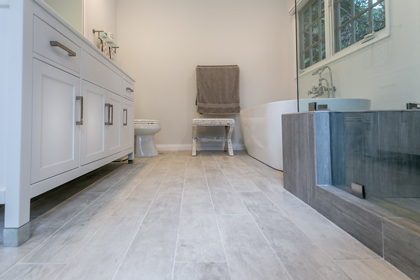 Idée de décoration pour un grand sauna minimaliste avec un placard à porte shaker, des portes de placard blanches, une baignoire indépendante, WC séparés, un carrelage blanc, un mur blanc, un sol en carrelage de céramique et un lavabo encastré.