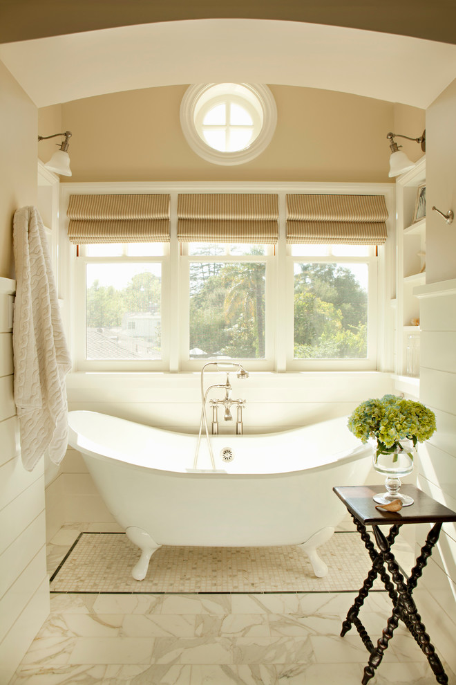 Immagine di una stanza da bagno stile marino con vasca con piedi a zampa di leone e pareti beige