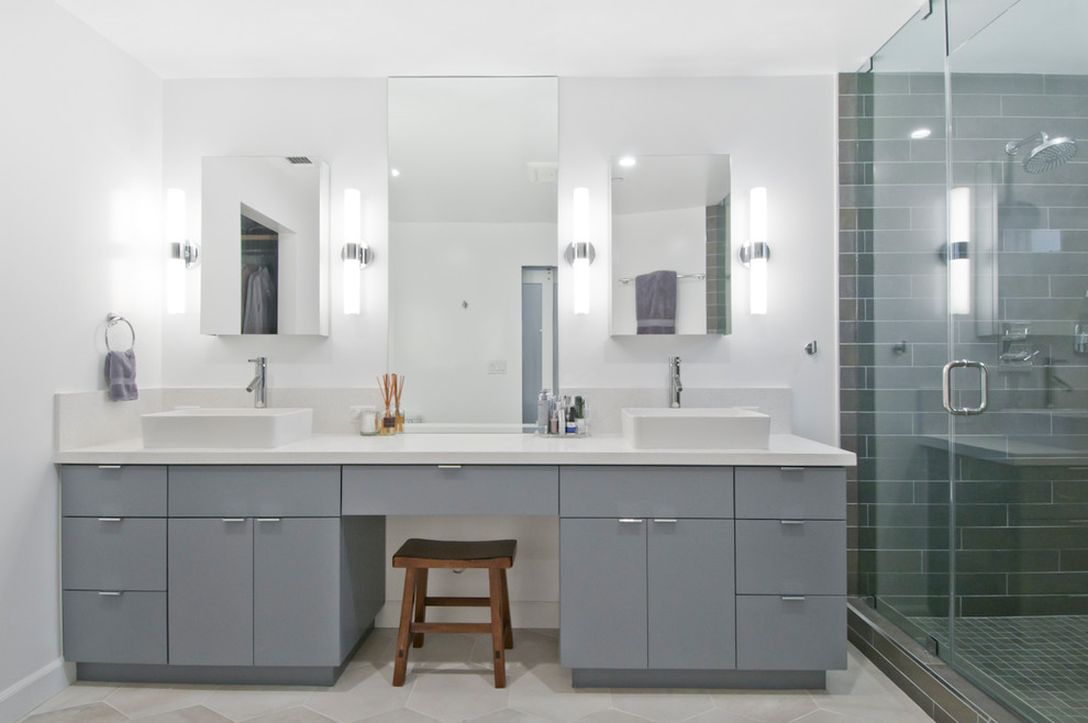 Bild på ett stort funkis vit vitt en-suite badrum, med luckor med glaspanel, grå skåp, en hörndusch, grå kakel, porslinskakel, grå väggar, cementgolv, ett fristående handfat, bänkskiva i akrylsten, grått golv och dusch med gångjärnsdörr