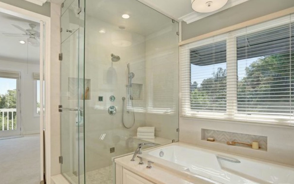 Photo of a large modern ensuite bathroom in Los Angeles with raised-panel cabinets, white cabinets, a built-in bath, a corner shower, grey walls, porcelain flooring, a submerged sink and marble worktops.