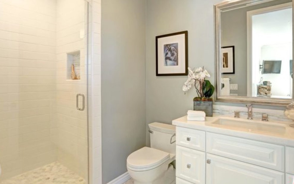 Photo of a small modern shower room bathroom in Los Angeles with raised-panel cabinets, white cabinets, an alcove shower, a one-piece toilet, white tiles, matchstick tiles, grey walls, a submerged sink and solid surface worktops.
