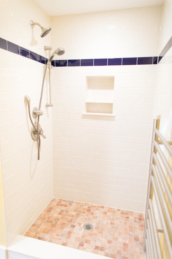 Bild på ett badrum, med vita skåp, vit kakel, tunnelbanekakel, gula väggar, klinkergolv i terrakotta, ett nedsänkt handfat, kaklad bänkskiva, rött golv och med dusch som är öppen