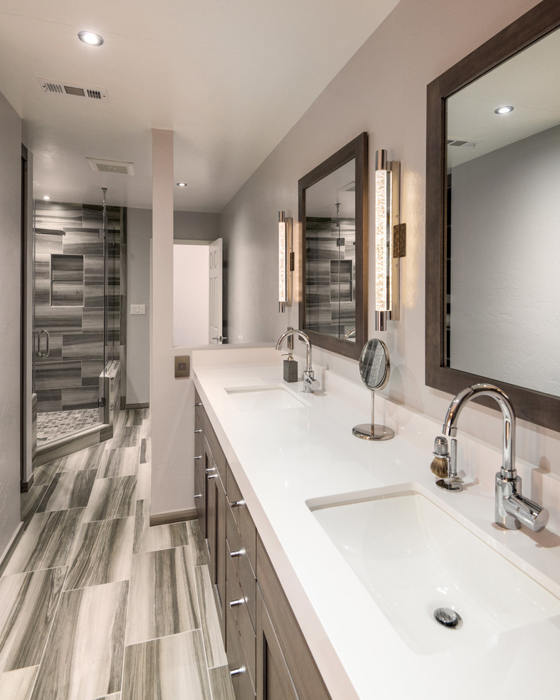This is an example of a large contemporary ensuite bathroom in San Diego with raised-panel cabinets, brown cabinets, a freestanding bath, a corner shower, a two-piece toilet, grey tiles, ceramic tiles, grey walls, ceramic flooring, a submerged sink, engineered stone worktops, grey floors and a hinged door.