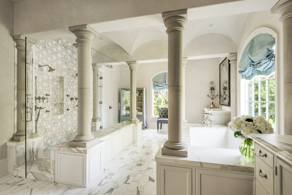 Immagine di una stanza da bagno con ante con riquadro incassato, ante grigie, vasca sottopiano, piastrelle grigie, piastrelle di marmo, pareti grigie, pavimento bianco e top grigio
