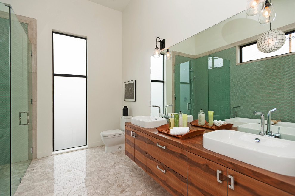 На фото: ванная комната в современном стиле с настольной раковиной, плоскими фасадами, фасадами цвета дерева среднего тона, зеленой плиткой и белыми стенами с