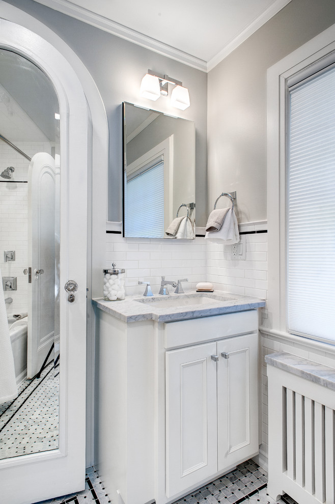 Idéer för att renovera ett litet vintage badrum, med luckor med profilerade fronter, vita skåp, ett badkar i en alkov, en toalettstol med separat cisternkåpa, svart och vit kakel, grå väggar, ett undermonterad handfat, marmorbänkskiva, en dusch/badkar-kombination, tunnelbanekakel och marmorgolv