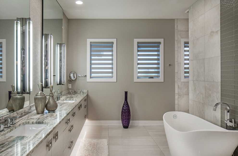 Design ideas for a contemporary bathroom in Omaha with flat-panel cabinets, grey cabinets, a freestanding bath, grey tiles, grey walls, a submerged sink and grey floors.