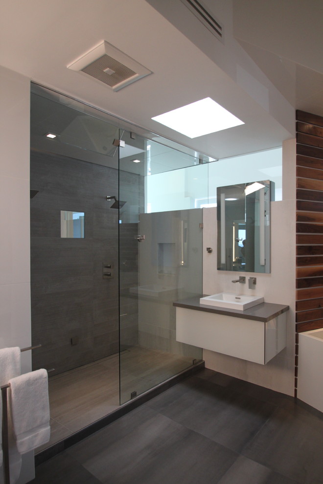 Aménagement d'une très grande salle de bain moderne avec un lavabo posé, un plan de toilette en quartz modifié, une baignoire indépendante, une douche double, WC suspendus, un carrelage gris, des carreaux de porcelaine, un mur blanc et un sol en ardoise.