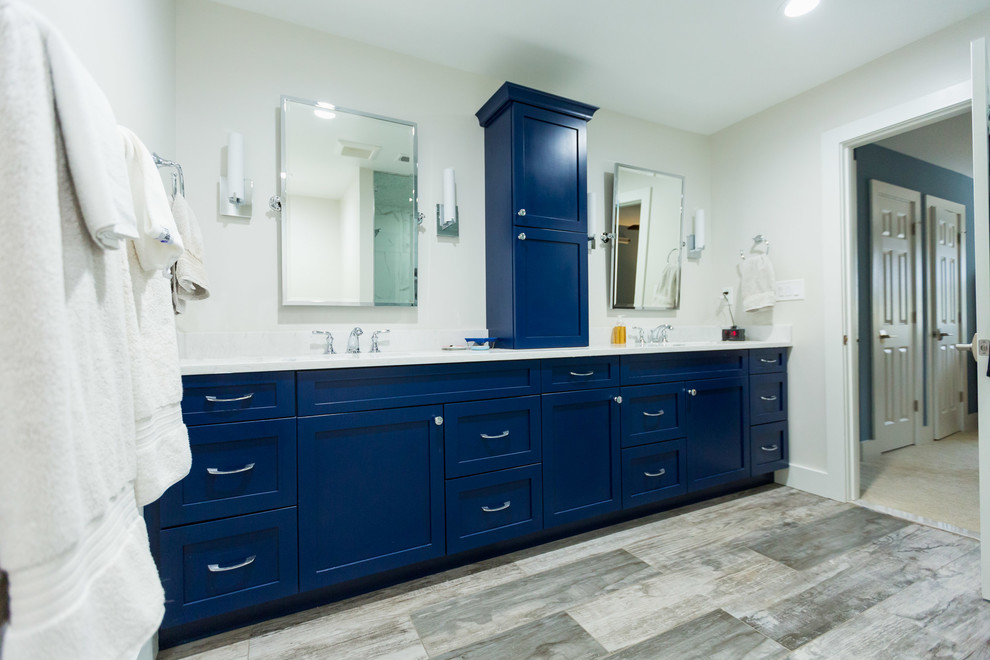 Источник вдохновения для домашнего уюта: большая главная ванная комната в стиле неоклассика (современная классика) с фасадами в стиле шейкер, ванной в нише, раздельным унитазом, бежевыми стенами, врезной раковиной, угловым душем, полом из фанеры, коричневым полом, душем с распашными дверями, синими фасадами, белой плиткой, мраморной плиткой, мраморной столешницей и белой столешницей