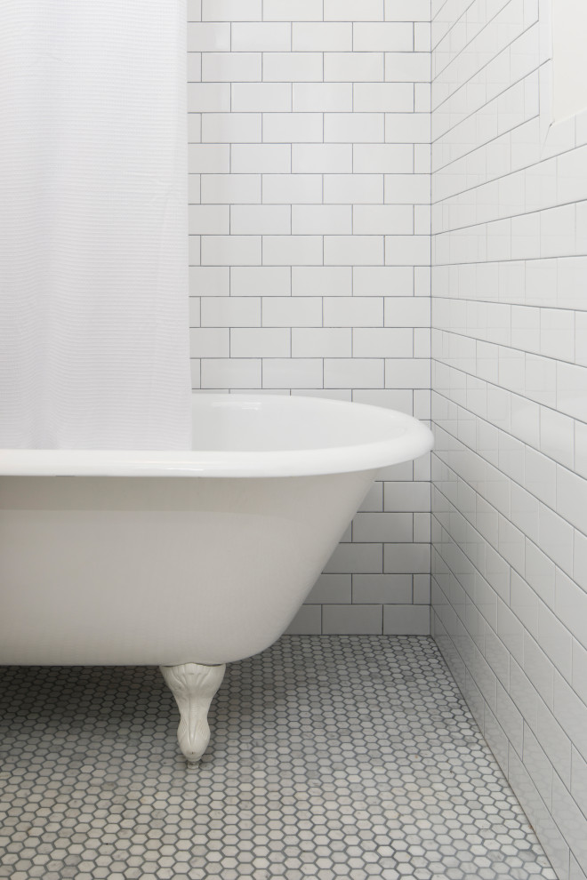 This is an example of a small traditional bathroom in New York with a claw-foot bath, white tiles, metro tiles, a wall-mounted sink, grey floors, a single sink and a floating vanity unit.