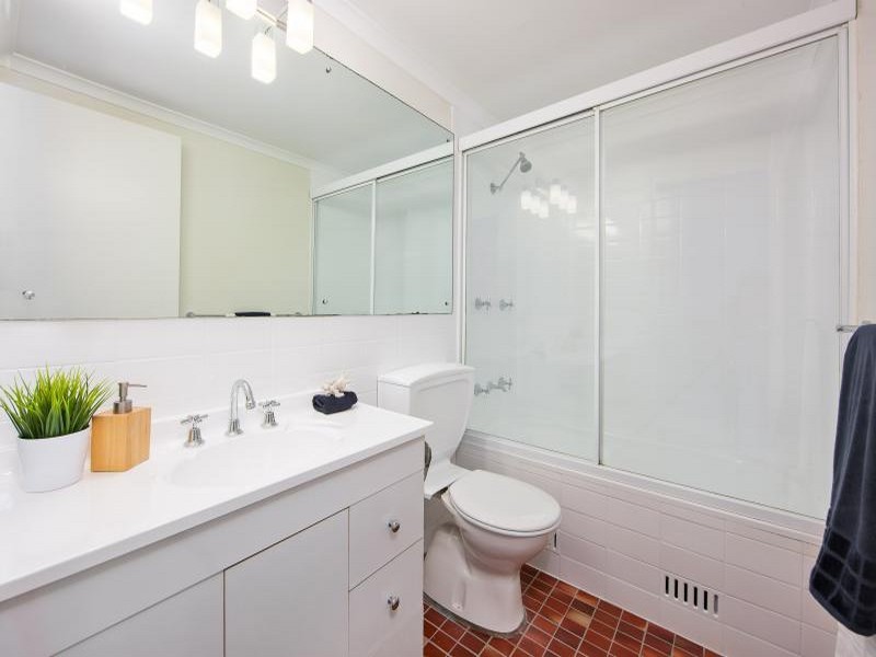 Réalisation d'une petite salle de bain design avec un placard à porte plane, des portes de placard blanches, une baignoire en alcôve, un combiné douche/baignoire, WC séparés, un carrelage blanc, des carreaux de porcelaine, un sol en carrelage de céramique, un lavabo intégré, un sol rouge et une cabine de douche à porte coulissante.