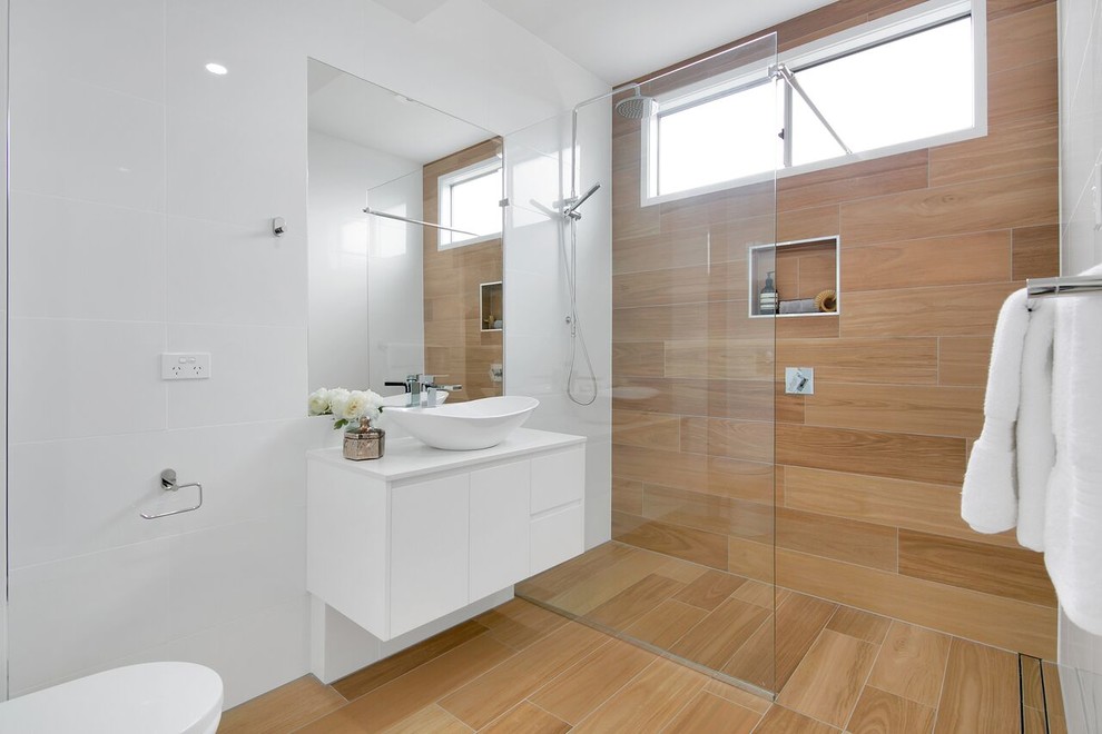 Modelo de cuarto de baño actual, de tamaño medio, con ducha empotrada, baldosas y/o azulejos marrones, baldosas y/o azulejos blancos, lavabo sobreencimera, suelo marrón, ducha abierta, armarios con paneles lisos, puertas de armario blancas, paredes blancas, aseo y ducha y encimeras blancas