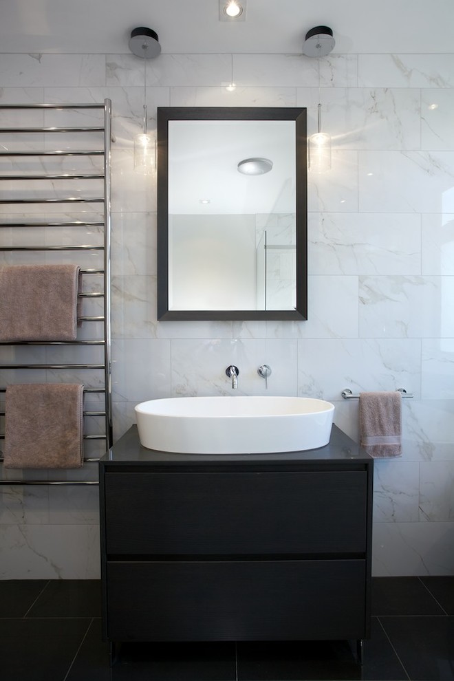 Modern bathroom in Auckland with freestanding cabinets, dark wood cabinets, engineered stone worktops, a freestanding bath, a built-in shower, a one-piece toilet, white tiles, porcelain tiles, white walls and porcelain flooring.
