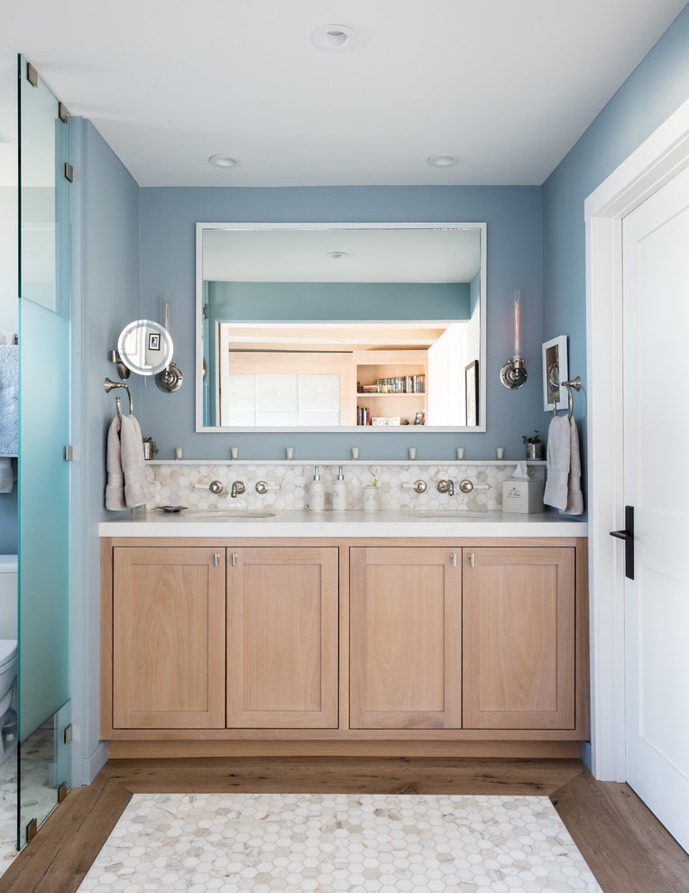 This is an example of a coastal ensuite bathroom in Los Angeles with shaker cabinets, medium wood cabinets, beige tiles, blue walls, medium hardwood flooring, a submerged sink, brown floors and white worktops.