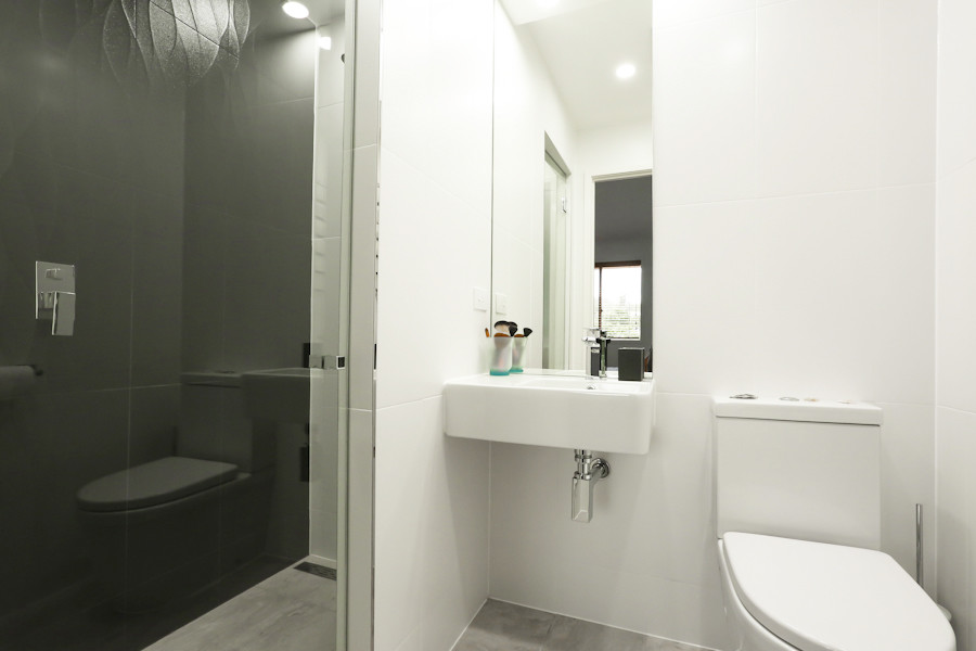 На фото: ванная комната среднего размера в стиле модернизм с раздельным унитазом, белыми стенами, душевой кабиной, серым полом, душевой комнатой, белой плиткой, керамогранитной плиткой, полом из керамической плитки, подвесной раковиной и душем с распашными дверями