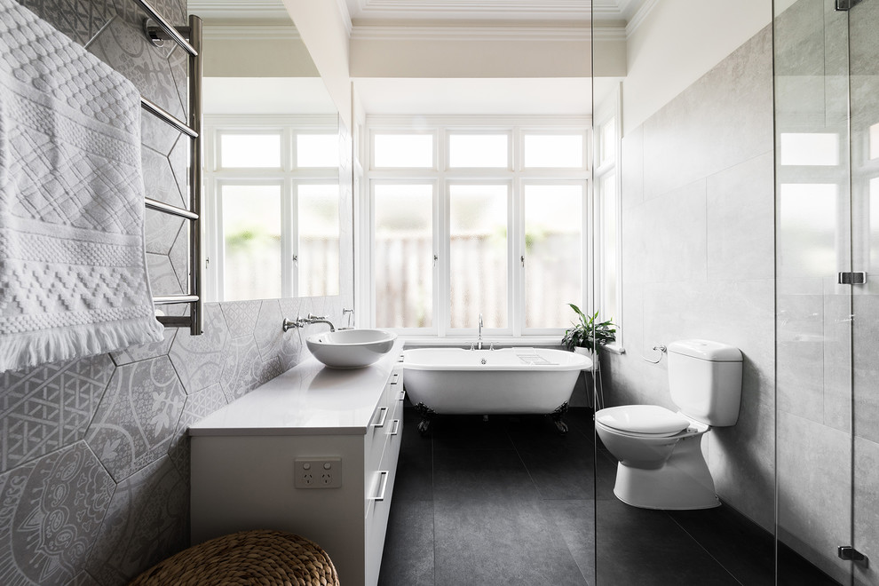 Exempel på ett mellanstort modernt en-suite badrum, med släta luckor, vita skåp, ett badkar med tassar, en öppen dusch, en toalettstol med hel cisternkåpa, grå kakel, keramikplattor, grå väggar, klinkergolv i keramik, ett fristående handfat, bänkskiva i kvarts, grått golv och dusch med gångjärnsdörr