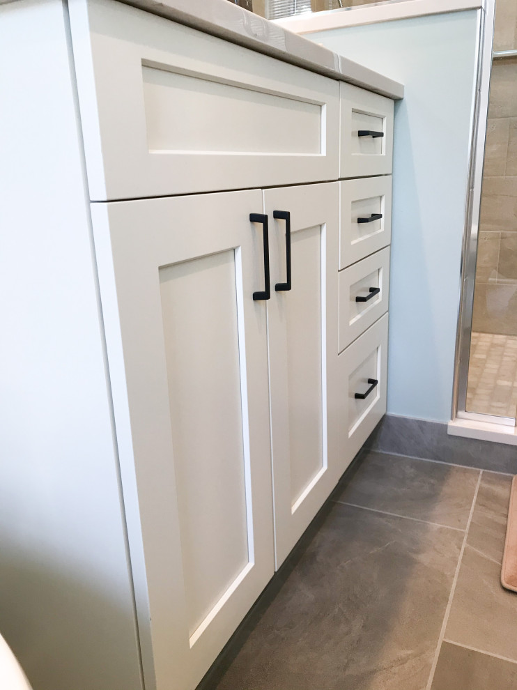 Photo of a small traditional ensuite bathroom in Chicago with shaker cabinets, white cabinets, a one-piece toilet, grey tiles, ceramic tiles, blue walls, porcelain flooring, a submerged sink, engineered stone worktops, grey floors, a hinged door, white worktops, a single sink and a freestanding vanity unit.