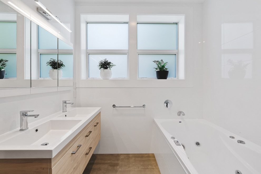 Idéer för att renovera ett mellanstort funkis vit vitt badrum med dusch, med släta luckor, beige skåp, ett badkar i en alkov, vit kakel, glasskiva, vita väggar, mellanmörkt trägolv, ett integrerad handfat och beiget golv