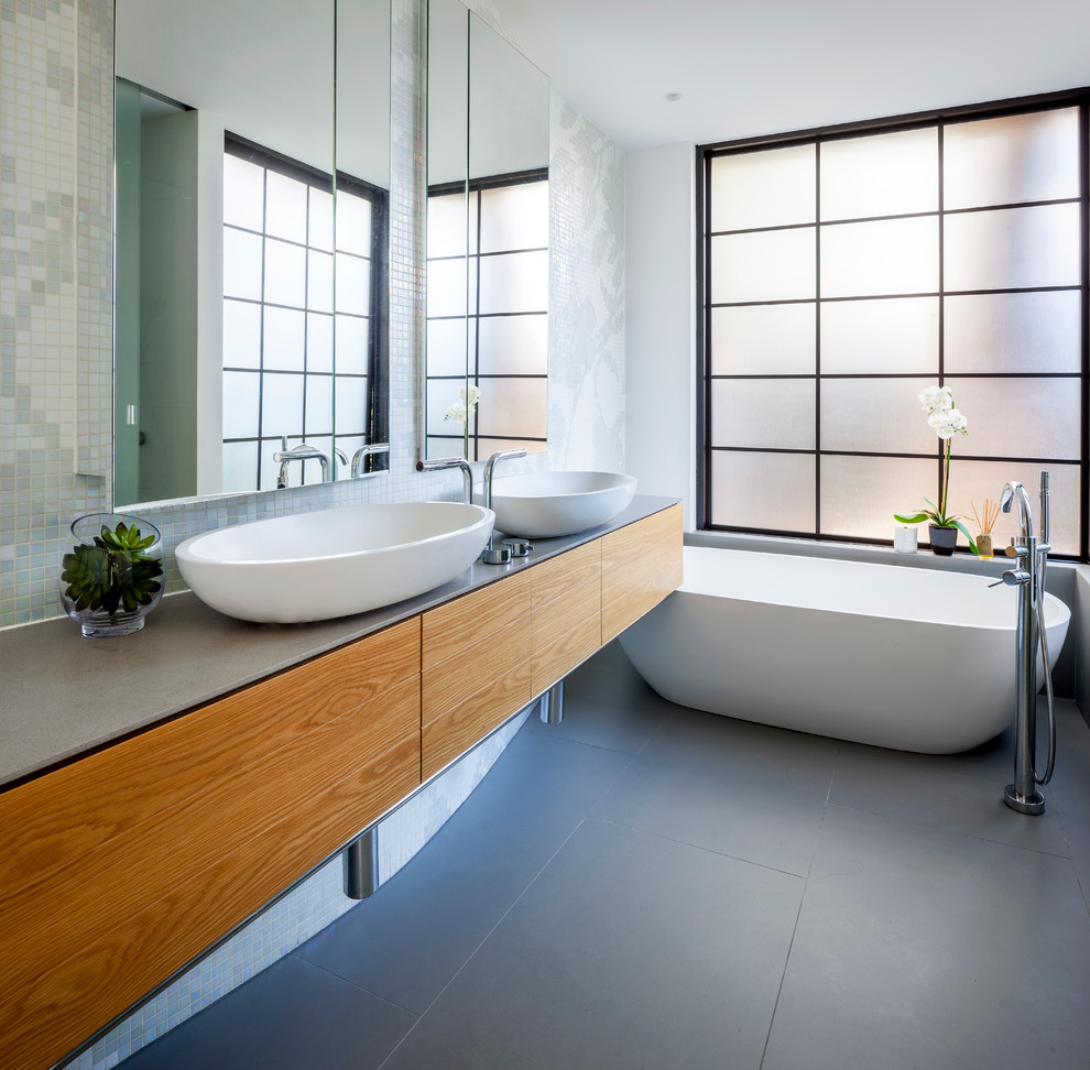 Aménagement d'une salle de bain principale contemporaine en bois brun de taille moyenne avec un placard avec porte à panneau surélevé, une baignoire indépendante, un carrelage gris, des carreaux de céramique et un plan de toilette en marbre.