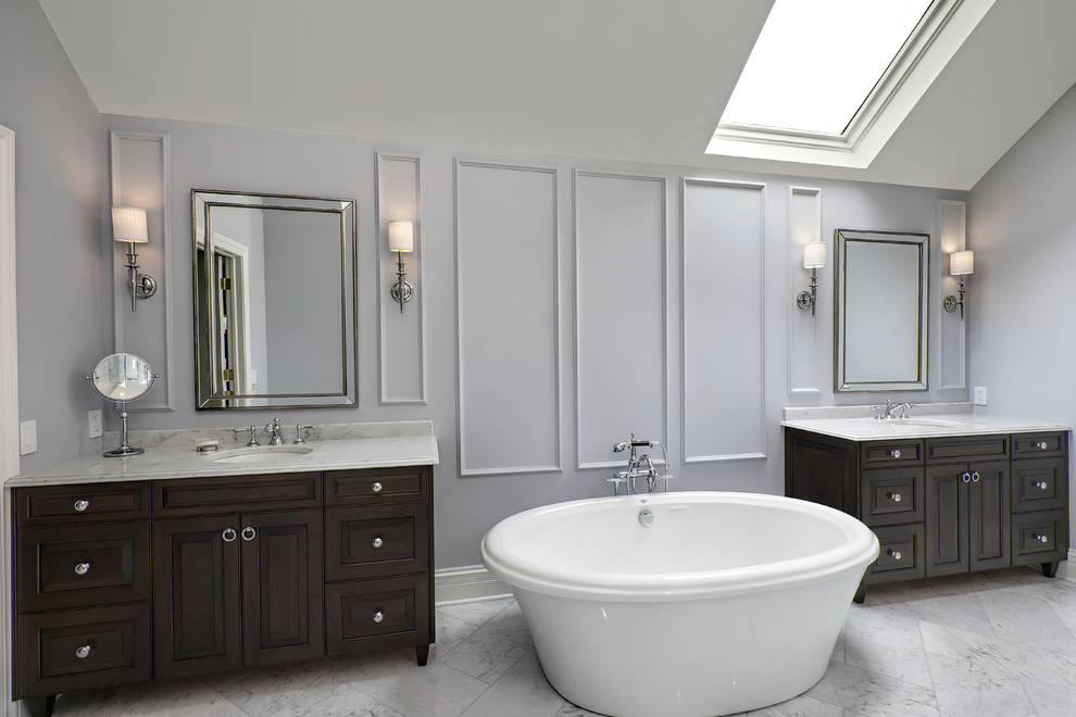 Стильный дизайн: главная ванная комната в классическом стиле с темными деревянными фасадами, отдельно стоящей ванной, серыми стенами, врезной раковиной, серым полом, серой столешницей и фасадами с выступающей филенкой - последний тренд