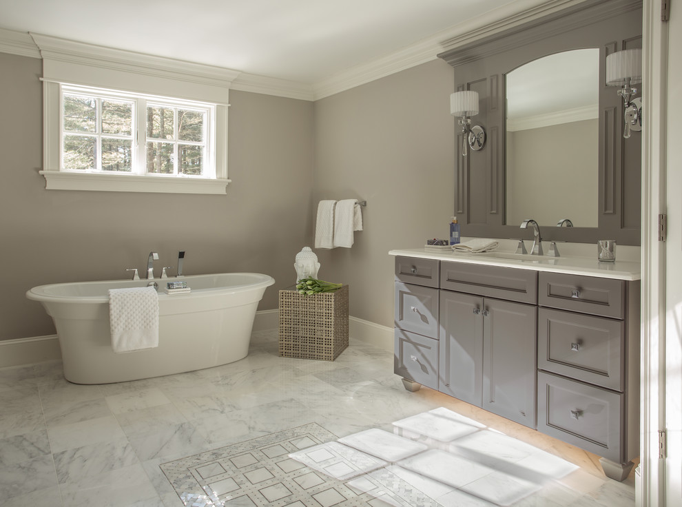 Aménagement d'une salle de bain craftsman avec des portes de placard grises, une baignoire indépendante, un carrelage blanc et un mur gris.