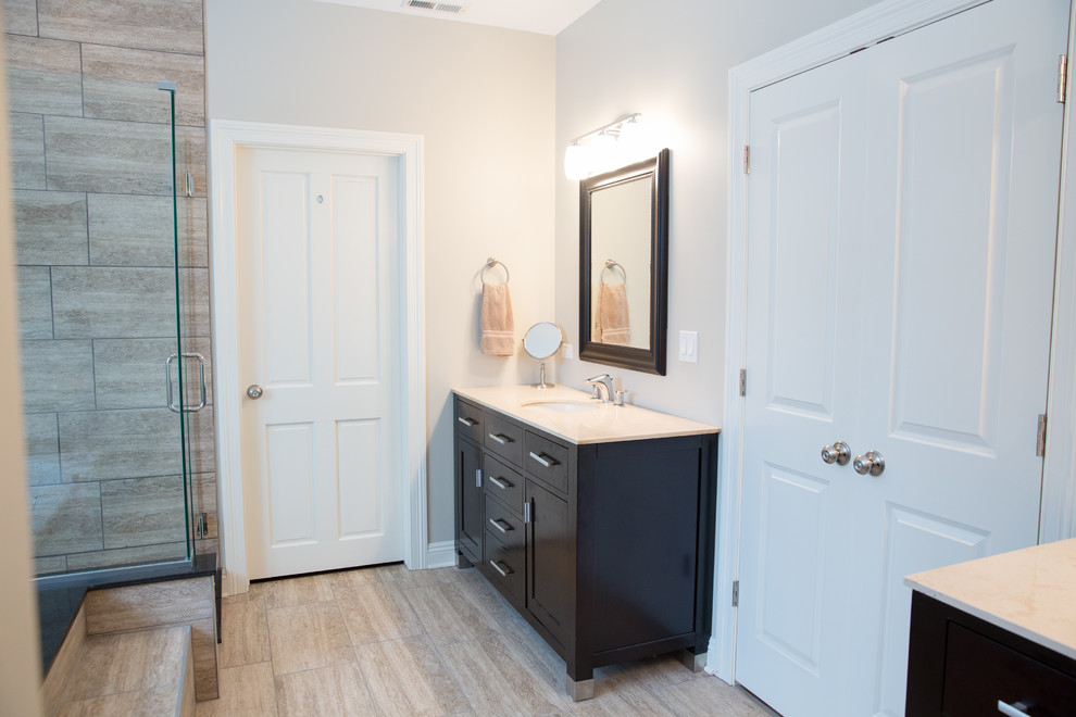 Bathroom - mid-sized traditional master beige tile and stone tile beige floor and laminate floor bathroom idea in Chicago with an undermount sink, flat-panel cabinets, dark wood cabinets, limestone countertops, a two-piece toilet, beige walls and a hinged shower door