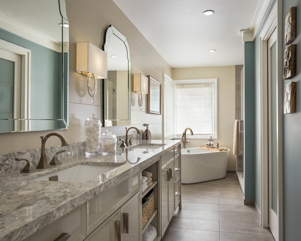 Exemple d'une douche en alcôve chic avec un placard avec porte à panneau encastré, des portes de placard grises, une baignoire indépendante, un mur beige, un lavabo encastré, un sol gris et un plan de toilette gris.