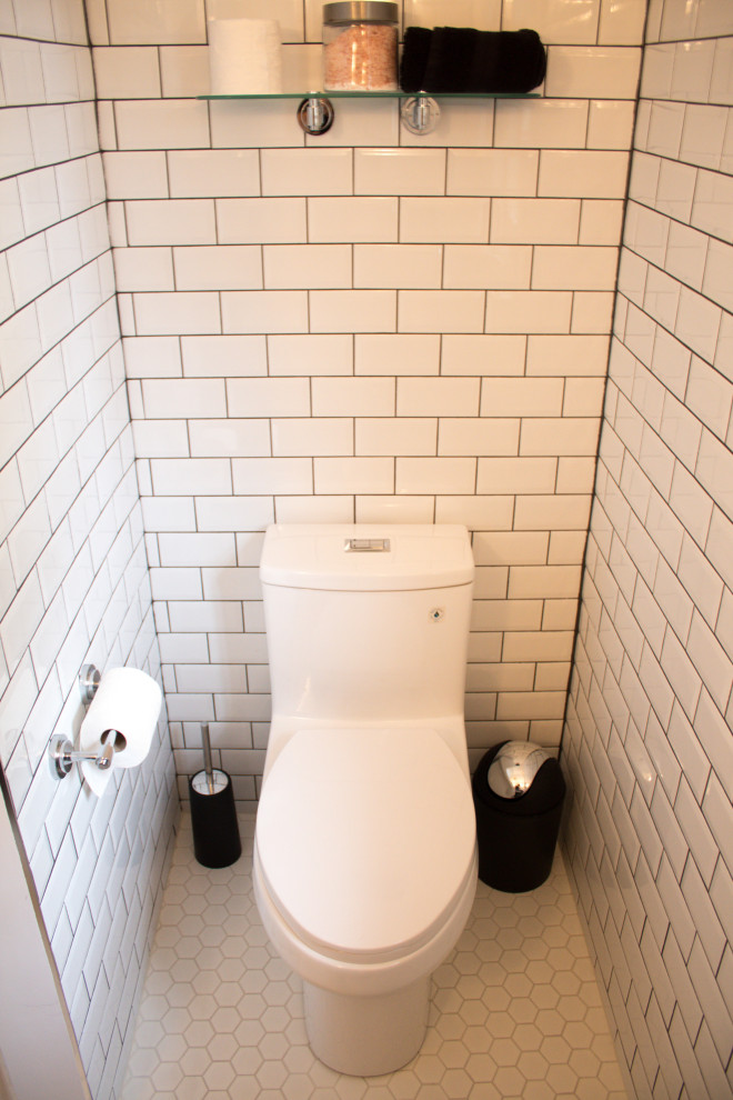 Idées déco pour un WC et toilettes classique de taille moyenne avec un placard en trompe-l'oeil, des portes de placard noires, WC à poser, un carrelage blanc, un carrelage métro, un mur blanc, un sol en carrelage de céramique, un plan de toilette en surface solide, un sol blanc et un plan de toilette blanc.