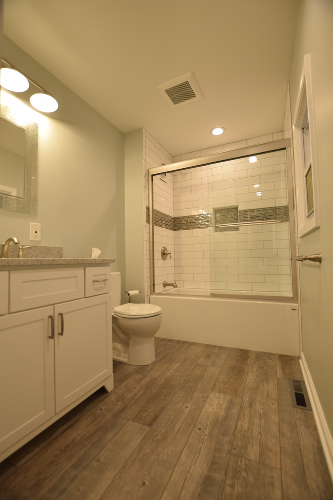 На фото: ванная комната среднего размера в стиле неоклассика (современная классика) с фасадами в стиле шейкер, белыми фасадами, ванной в нише, душем над ванной, раздельным унитазом, белой плиткой, плиткой кабанчик, зелеными стенами, полом из керамогранита, душевой кабиной, врезной раковиной, столешницей из искусственного кварца, серым полом и душем с раздвижными дверями