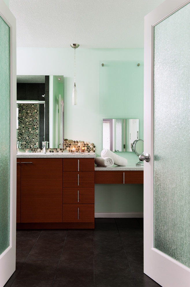 Cette image montre une salle de bain design en bois foncé avec un placard à porte plane, une plaque de galets et un mur vert.