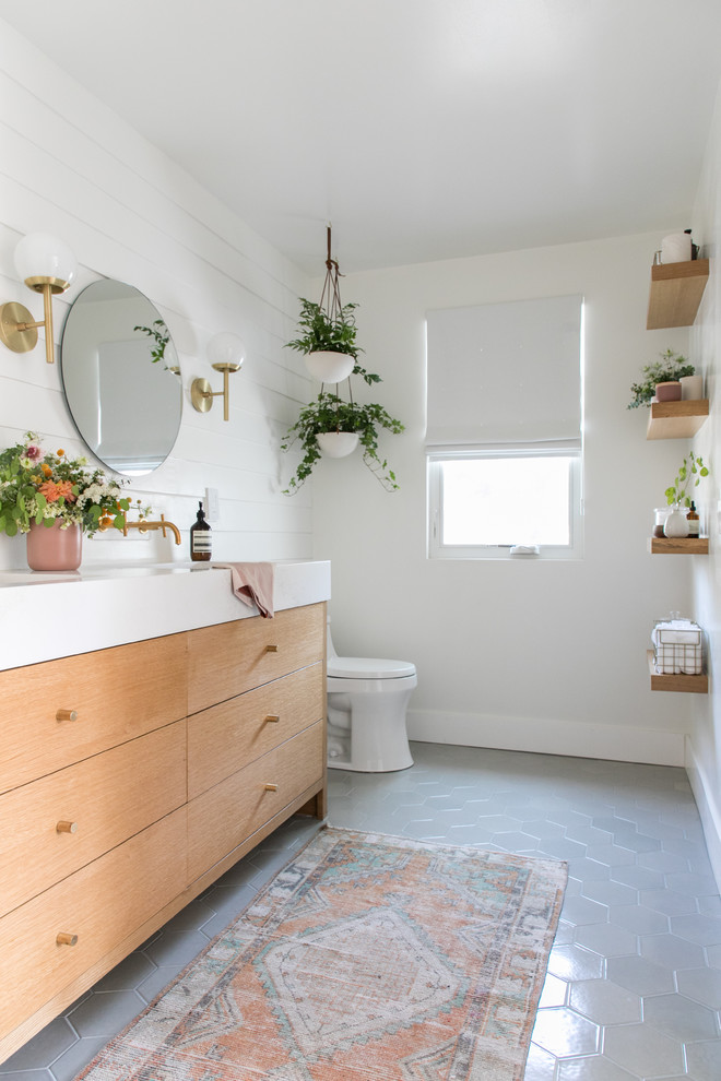 Modelo de cuarto de baño clásico renovado con paredes blancas, suelo de baldosas de cerámica, suelo gris, armarios con paneles lisos, puertas de armario de madera oscura y encimeras blancas