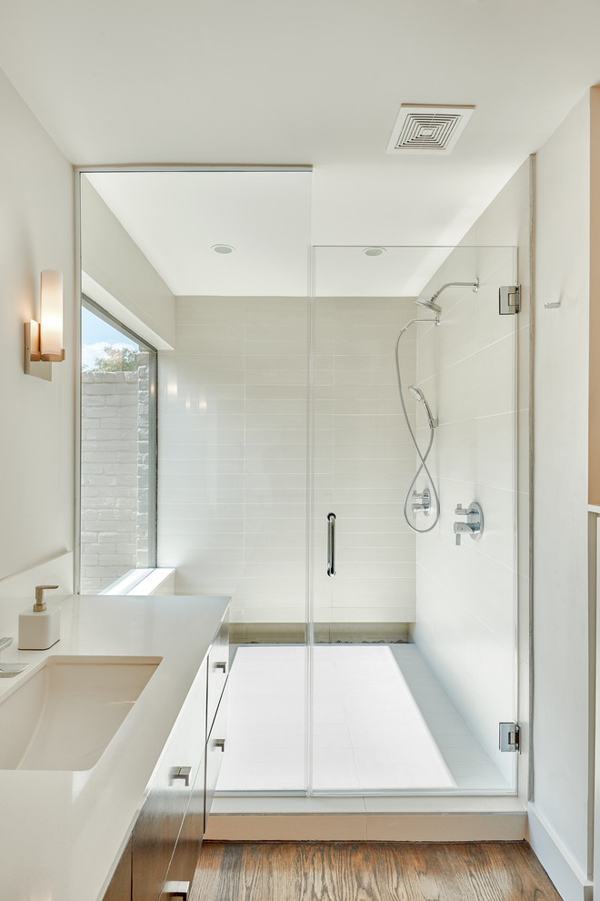 Пример оригинального дизайна: ванная комната в современном стиле с врезной раковиной, плоскими фасадами, душем в нише, белой плиткой, темным паркетным полом, керамической плиткой и окном