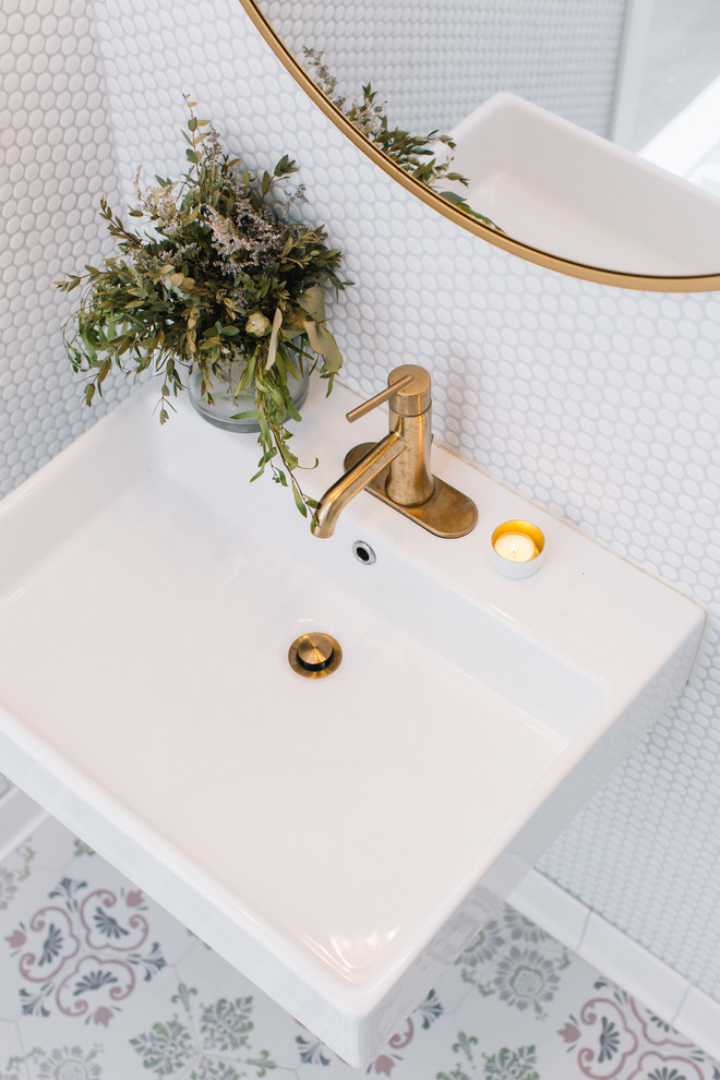 На фото: ванная комната в современном стиле с белой плиткой, подвесной раковиной и разноцветным полом с