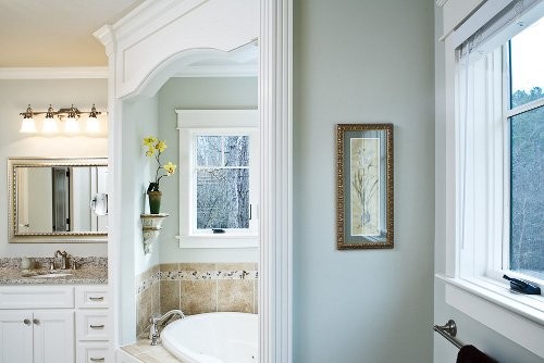 Ispirazione per una grande stanza da bagno padronale classica con ante lisce, ante bianche, vasca ad angolo, piastrelle beige, piastrelle in ceramica, pareti blu, lavabo sottopiano e top in granito