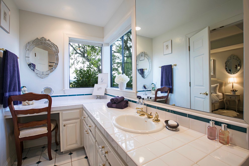 This is an example of a medium sized contemporary ensuite bathroom in San Francisco with shaker cabinets, white cabinets, a freestanding bath, a shower/bath combination, a wall mounted toilet, white tiles, porcelain tiles, white walls, porcelain flooring, a built-in sink, tiled worktops, white floors, a hinged door and white worktops.